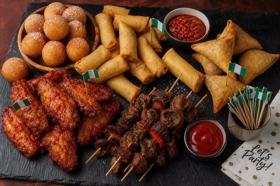 Nigerian small chops platter with puff puff, spring rolls, samosas, peppered gizzard and chicken wings